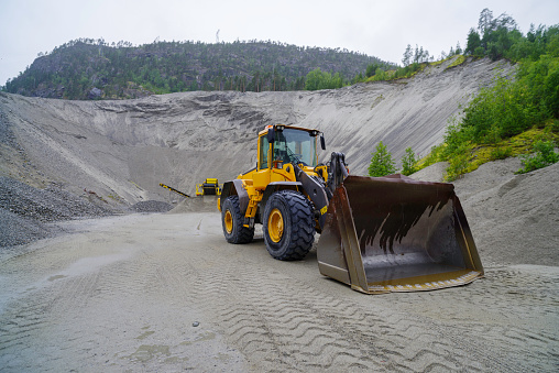 yellow excavator with an enormous scoop in a sand quarry