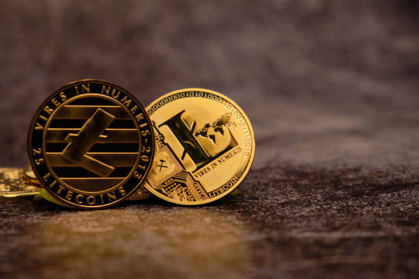 Close-up of the Litecoin Cryptocurrency with a golden reflection on the table. Close-up of the Litecoin Cryptocurrency with a golden reflection on the table and with an out of focus background. litecoin stock pictures, royalty-free photos & images