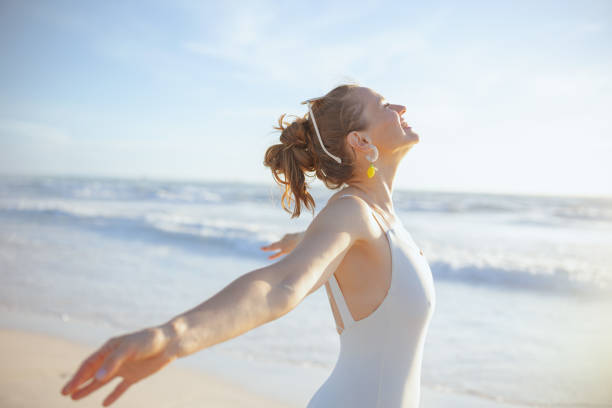 happy modern woman in white swimsuit at beach relaxing stock photo