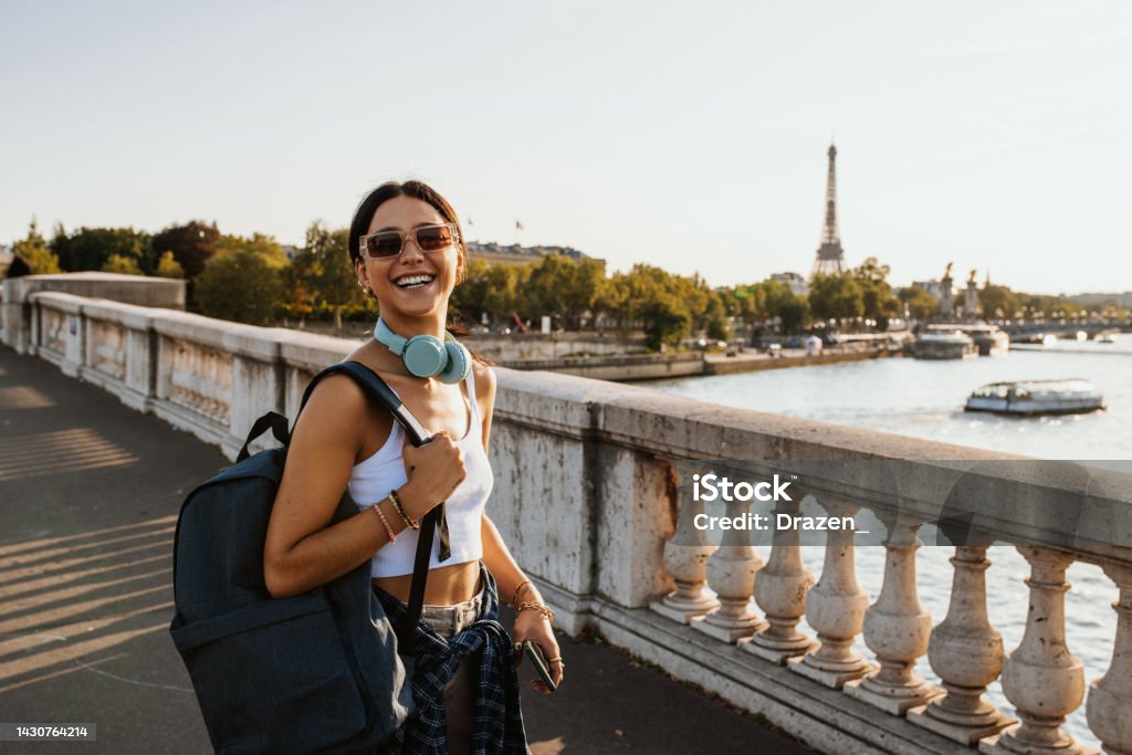 Young traveler enjoying city break in Paris in summer, carrying backpack and smiling Beautiful millennial woman in Paris Paris - France Stock Photo
