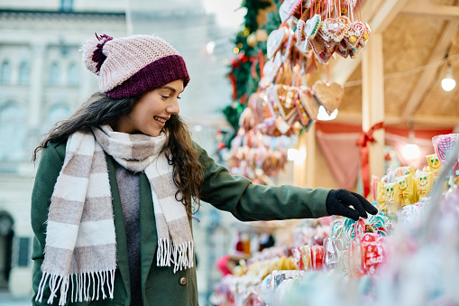 Happy woman choosing candies on Christmas market during winter holidays.