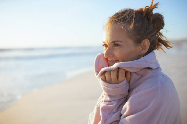 smiling elegant woman at beach in evening relaxing stock photo