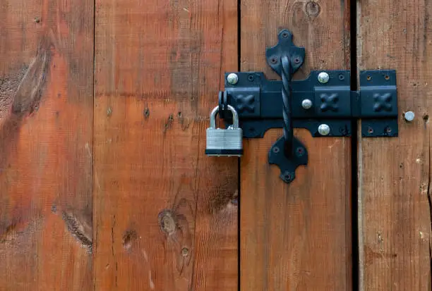 Closed metal padlock close-up on latch wooden door