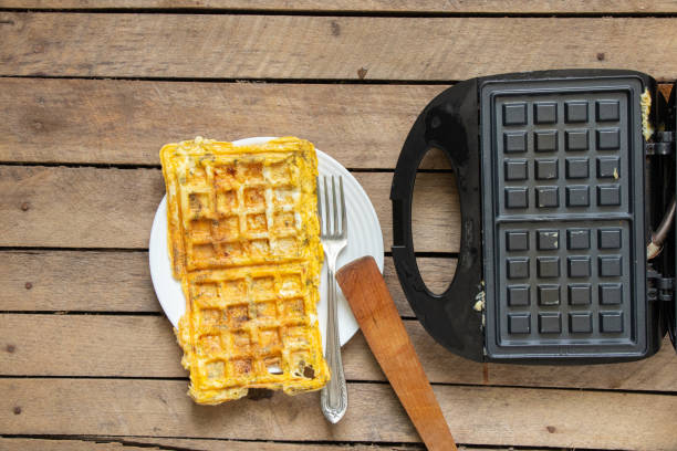 istock fry scrambled eggs with cheese and spices in a waffle iron on a wooden table in the kitchen, boil scrambled eggs in a waffle iron 1430765059