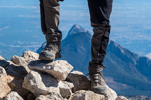 High altitude mountainous region. In the background is a triangular, pointed, majestic mountain. The focus is on the shoes. The background is out of focus with the mountain. The mountain landscape between the model's legs.
