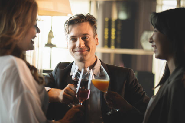 People young man and woman smiling and laughing happy Clink a glass of champagne and wine to celebrate at a party in the bar restaurant stock photo