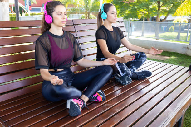 Friends practicing yoga with wireless headphones stock photo