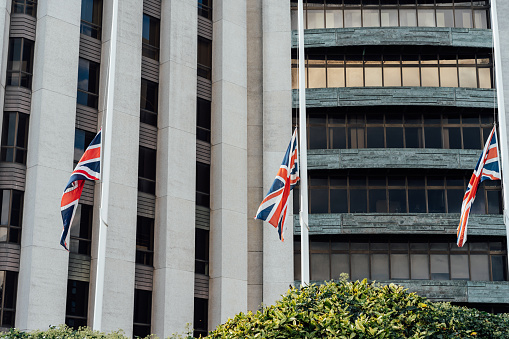Three half-mast British Union Flags in front of administrative building. Selective focus copy space