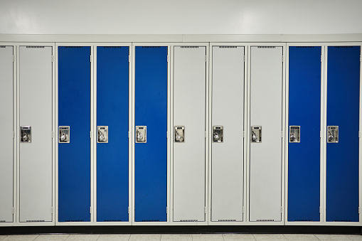 Row of white and blue student lockers in the hallway of a school with no people