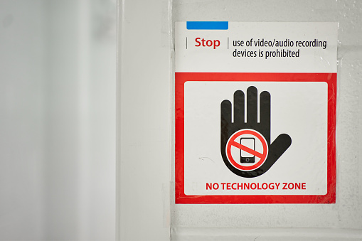 Sign prohibiting the use of mobile phones and other electronic equipment on a wall in a school hall
