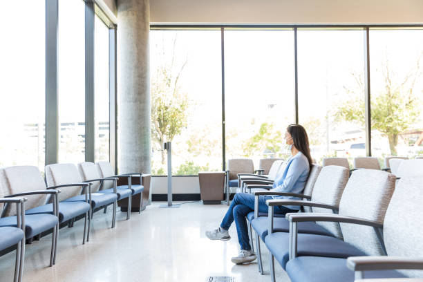 Adult female sits in the waiting room The adult female patient sits in the waiting room of the medical clinic alone. waiting room stock pictures, royalty-free photos & images
