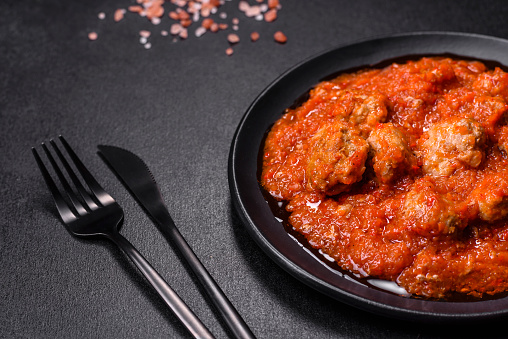 Delicious meatballs made from ground beef in a spicy tomato sauce served in a black pan