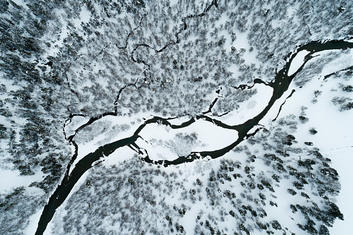 Top view of a mountain river running through a winter forest