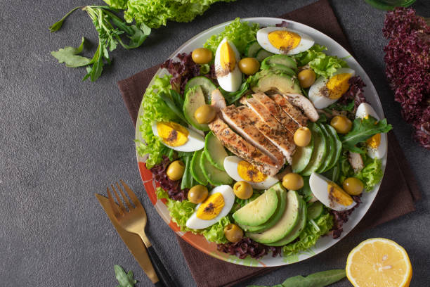istock Salad with avocado, chicken, eggs, olives and lettuce leaves on gray background, Copy space 1430773594