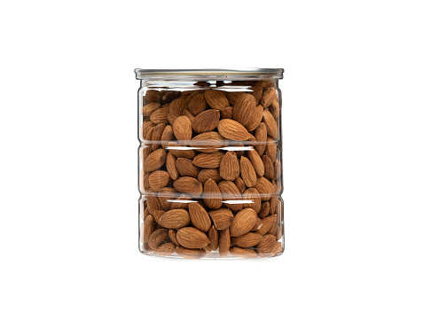Transparent jar full of almonds on a white background. Copy space.
