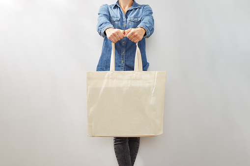 Unrecognizable young woman in denim shirts with a blank canvas eco tote bag