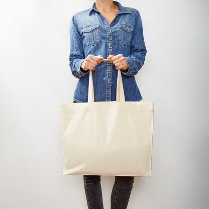 Unrecognizable young woman in denim shirts with a blank canvas eco tote bag
