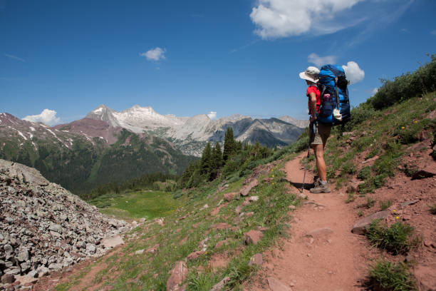 Woman backpacker on Buckskin Pass, Four Pass backpacking trip around the Maroon Bells. Snowmass Mountain in the distance. Aspen, Colorado.