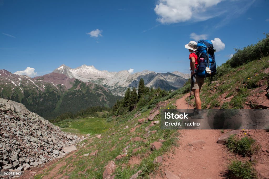 Woman backpacker on Buckskin Pass, Four Pass backpacking trip around the Maroon Bells. Snowmass Mountain in the distance. Aspen, Colorado. Hiking Stock Photo