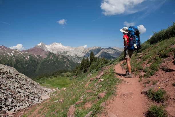 Woman backpacker on Buckskin Pass, Four Pass backpacking trip around the Maroon Bells. Snowmass Mountain in the distance. Aspen, Colorado. stock photo
