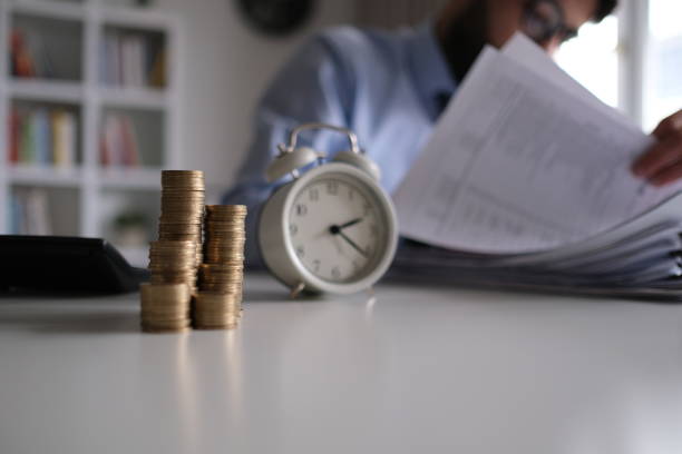 Businessman writing notes in documents model on stack of coins, in business, saving money