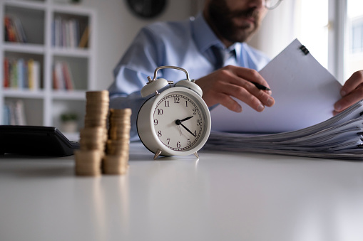 Businessman writing notes in documents model on stack of coins, in business, saving money