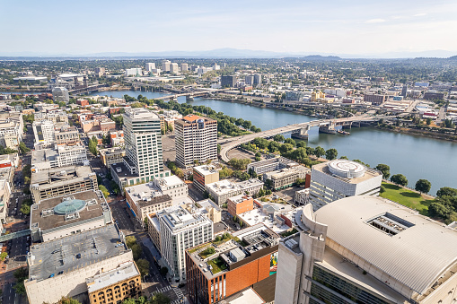 Aerial of downtown Portland on a sunny day with views of the business district with skyscrapers and the Pearl district with Hawthorne Bridge on Willamette river in the background