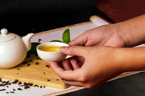 Hands holding a small bowl of green tea