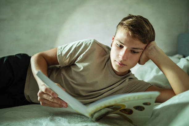 Teenage boy studying in bed