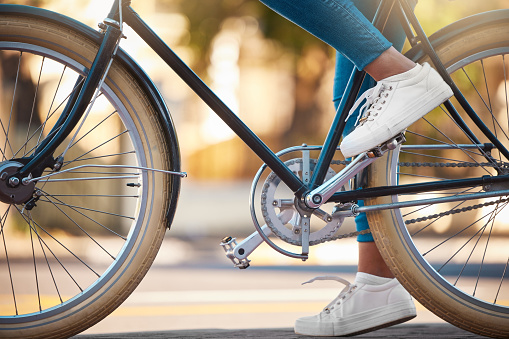 Bike, shoes and cycling with a woman cyclist riding her bicycle outside on the road or street during the day. Sport, exercise and fitness with a female rider on transport with wheels and pedals