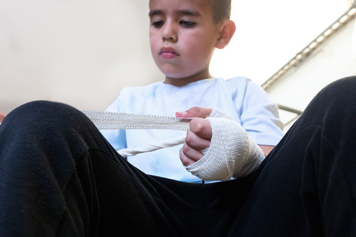 Latino boy unrolling his bandages for boxing training