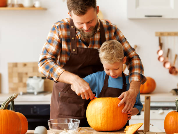 istock Son and dad making Jack-o-Lantern together at home, carving Halloween pumpkin 1430802956