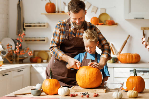 istock Son and dad making Jack-o-Lantern together at home, carving Halloween pumpkin 1430804594