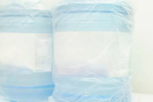 Photo of Two plastic containers of water are inside a transparent plastic bag. Fresh.  Freshness. Full. Gallon. Health. Healthy. High. Home. Label. Large. Liquid. Mineral. New. Object.