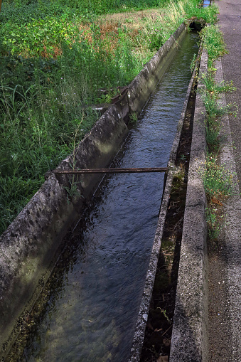 concrete irrigation  canal for farms, running alongside the main street in downtown Vedelago, Italy