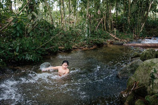 Child playing in the water and having fun surrounded by nature and many colors