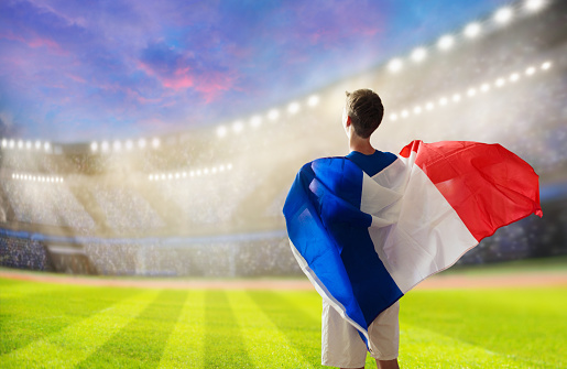 France football supporter on stadium. French fan on soccer pitch watching team play. Young player with flag and national jersey cheering for France. Championship game.