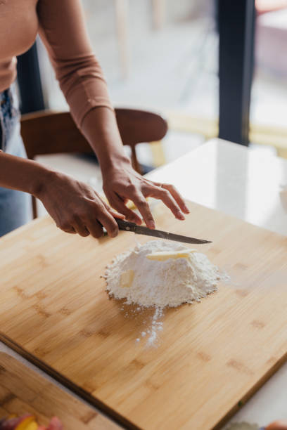 A cropped photo of an anonymous Latin-American woman making a cake by adding some butter into flour.