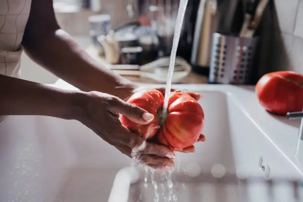 Photo of A Side View Of An Unrecognizable Woman Washing A Beautiful Ripe