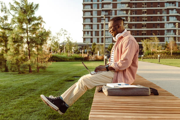 istock Side view of a young man sitting outdoors and using a laptop 1430817001