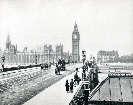 This aerial black and white photograph presents a timeless view over London's iconic skyline. Dominating the scene is the majestic silhouette of the Houses of Parliament and the iconic clock tower, Big Ben, standing as sentinels over the River Thames. The river's calm waters reflect the grandeur of these historical structures, while the sprawling urban landscape stretches into the horizon, peppered with both modern and ancient buildings. The overcast sky casts a diffuse light, lending the city a soft, ethereal quality and highlighting the intricate gothic architecture. This image encapsulates the enduring legacy and the unchanging face of London amidst the ever-evolving tapestry of city life, inviting the viewer to ponder the stories and history woven into the fabric of this grand metropolis.