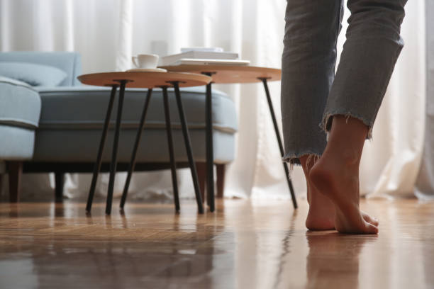 Barefoot woman on the wooden floor. Concept of the underfloor heating in the apartment. Barefoot woman on the wooden floor. Concept of the underfloor heating in the apartment. heat home interior comfortable human foot stock pictures, royalty-free photos & images