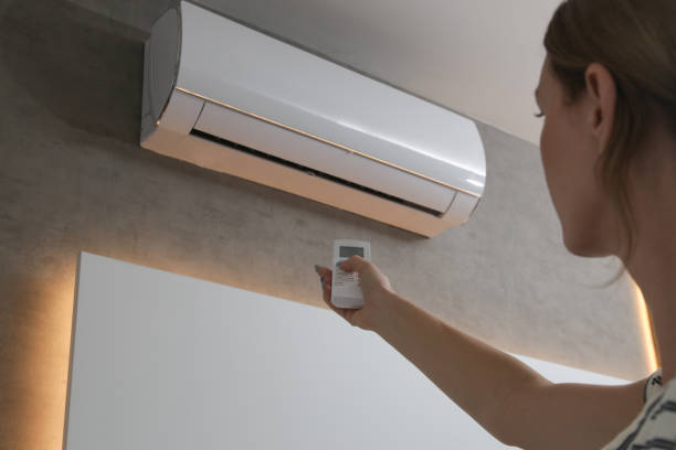 istock Young woman adjusting air conditioner with remote control 1430820183