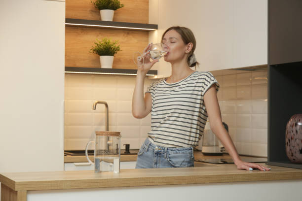 Young woman drinking water from glass in the kitchen stock photo