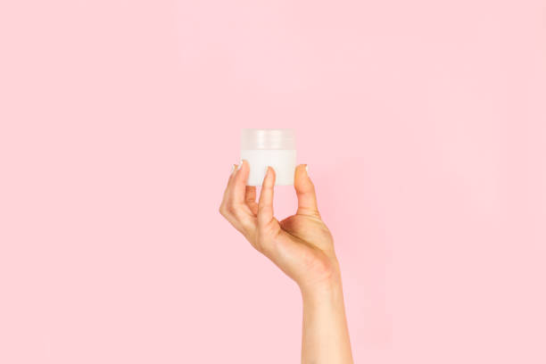 istock Woman hand holding a moisturizer cream bottle on a pink background 1430830655