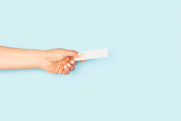 istock Woman hand holding a blank white personal card on a light blue backgroud 1430830828