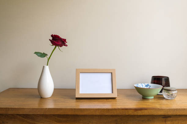 istock Small blank picture frame on oak side table with single red rose 1430840707