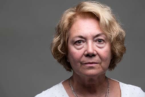 Serious Senior Woman front mugshot on gray background