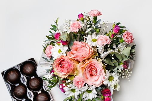 Defocus flowers and chocolate. Flowers, bridal bouquet close-up. Decoration of roses, peonies and ornamental plants. Gift for Valentines day Women day. Mothers Day. White background. Out of focus.