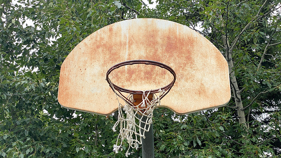 A basketball hoop sits old, rusty, and well used. Seemingly abandoned this basketball hoop has seen many days.